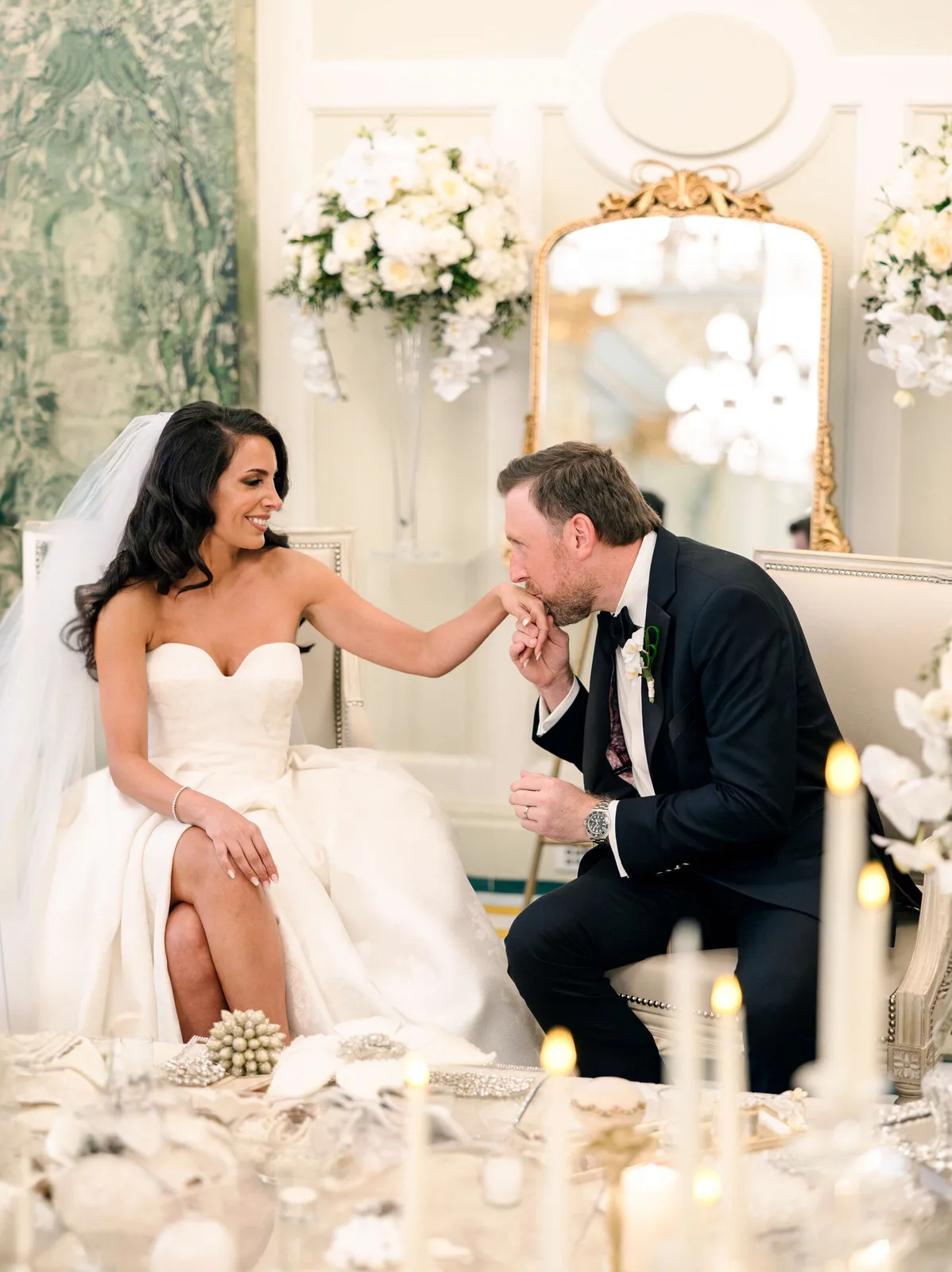 Le marié embrasse la main de la mariée dans un décor fleuri