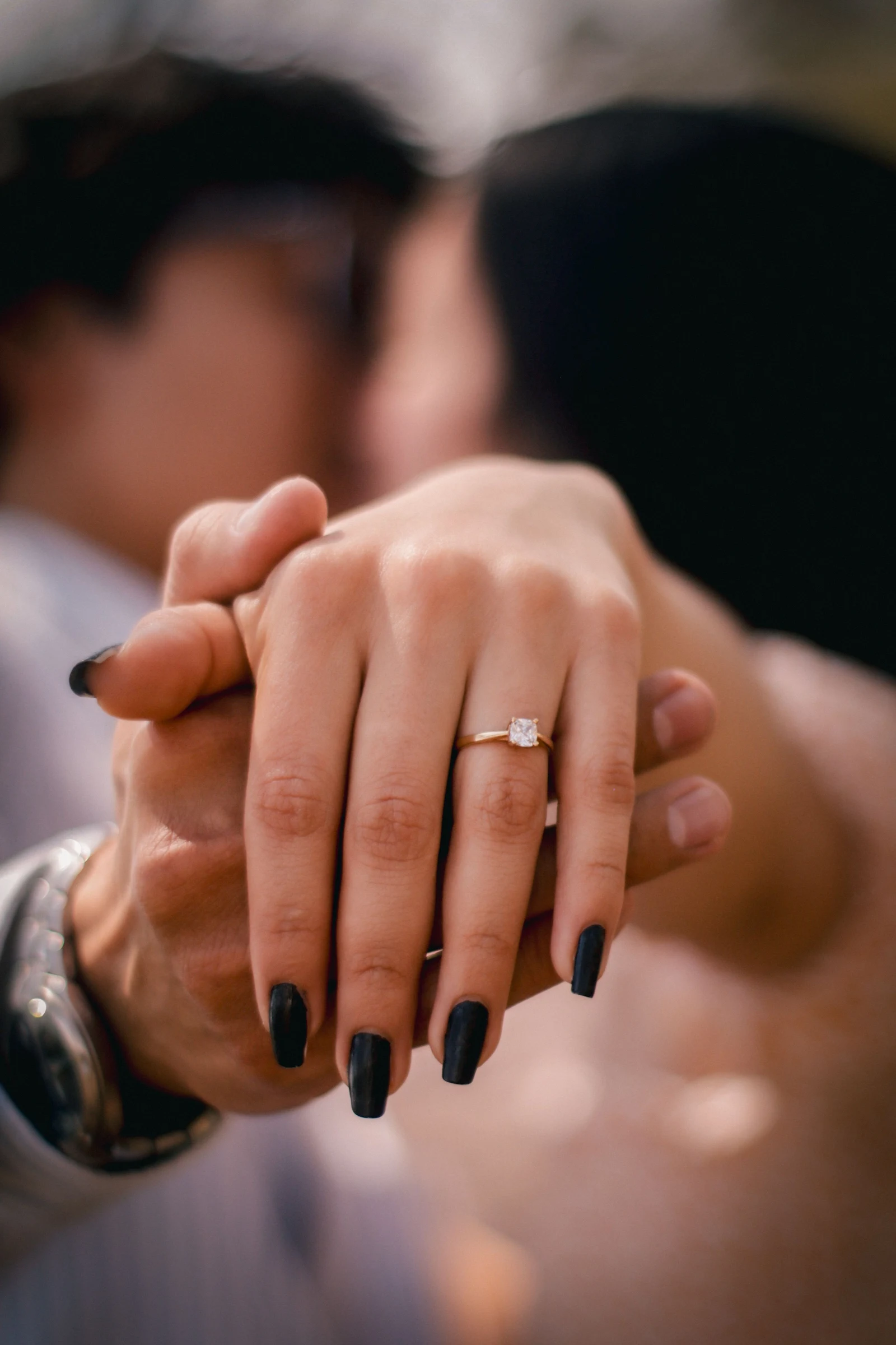 Mains enlacées d’un couple, bague de fiançailles au doigt