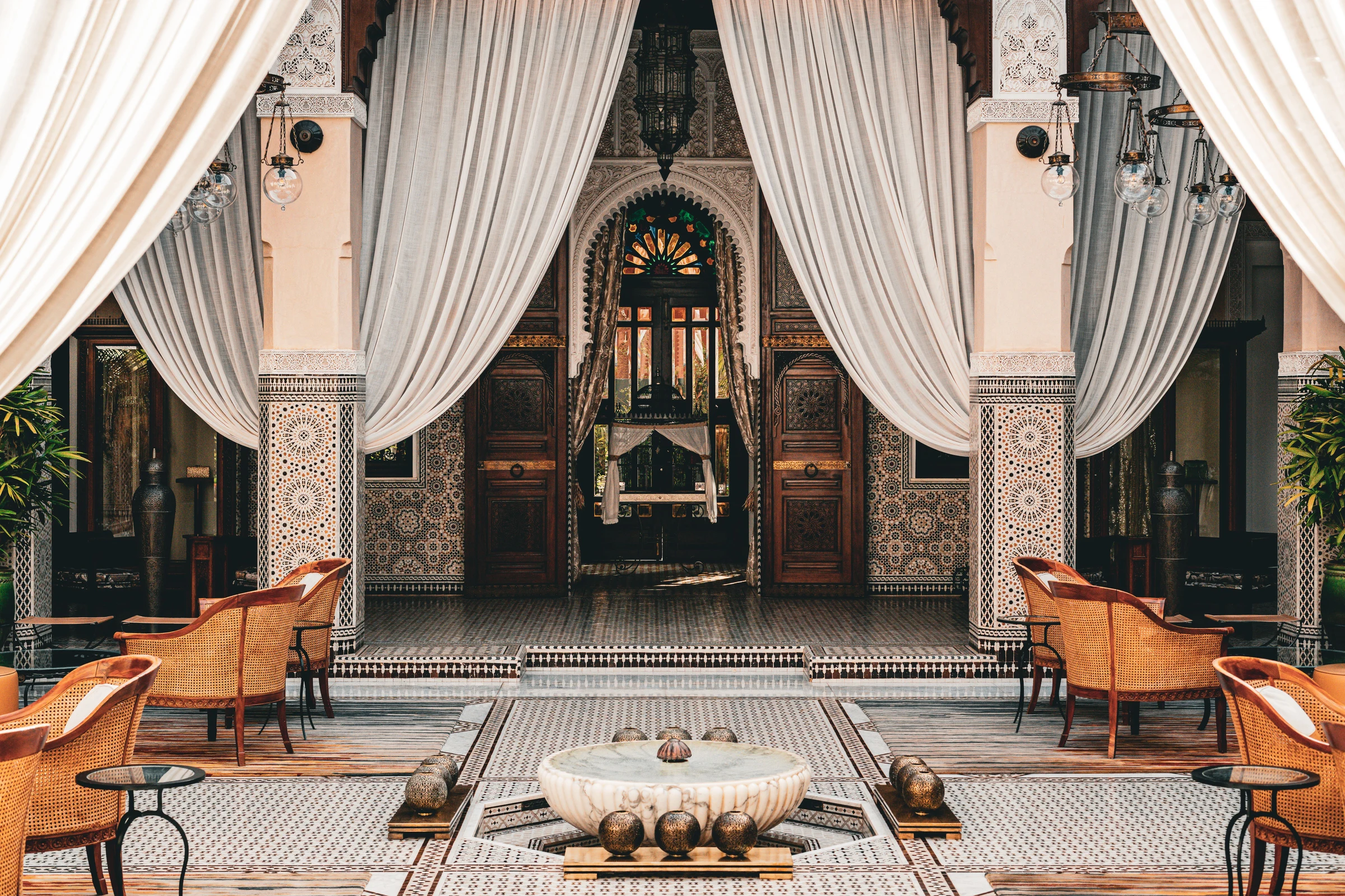 Cour d’un palais marocain avec rideaux blancs et salon