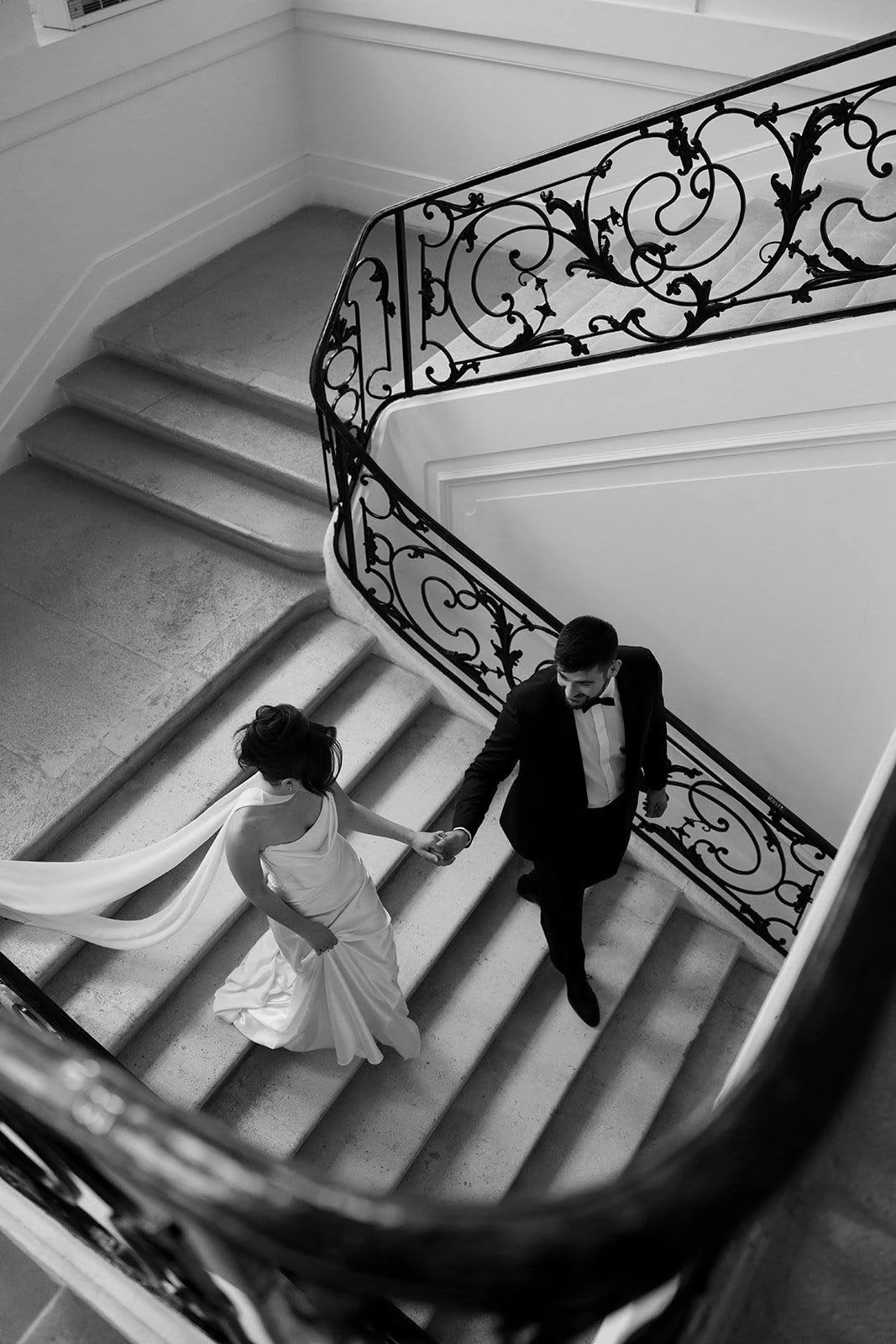 Les mariés descendent un escalier en colimaçon, en noir et blanc