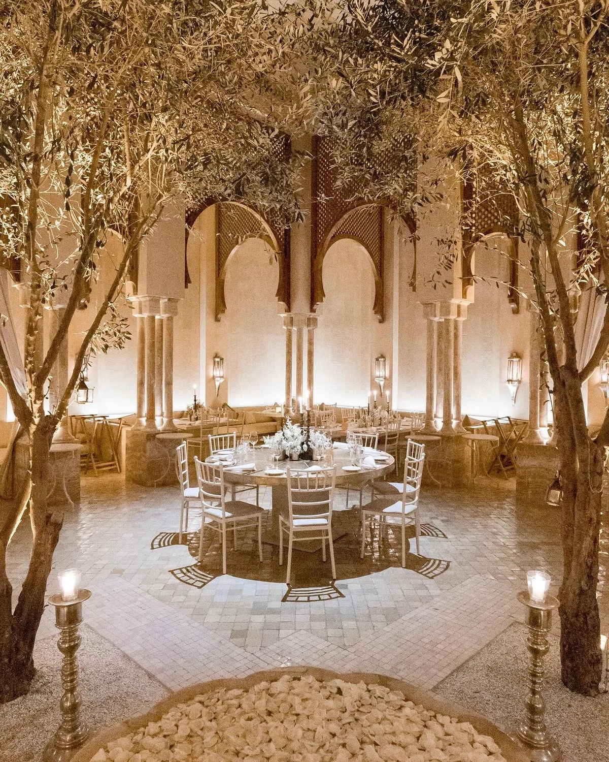 Table dressée sous des arbres illuminés dans une cour