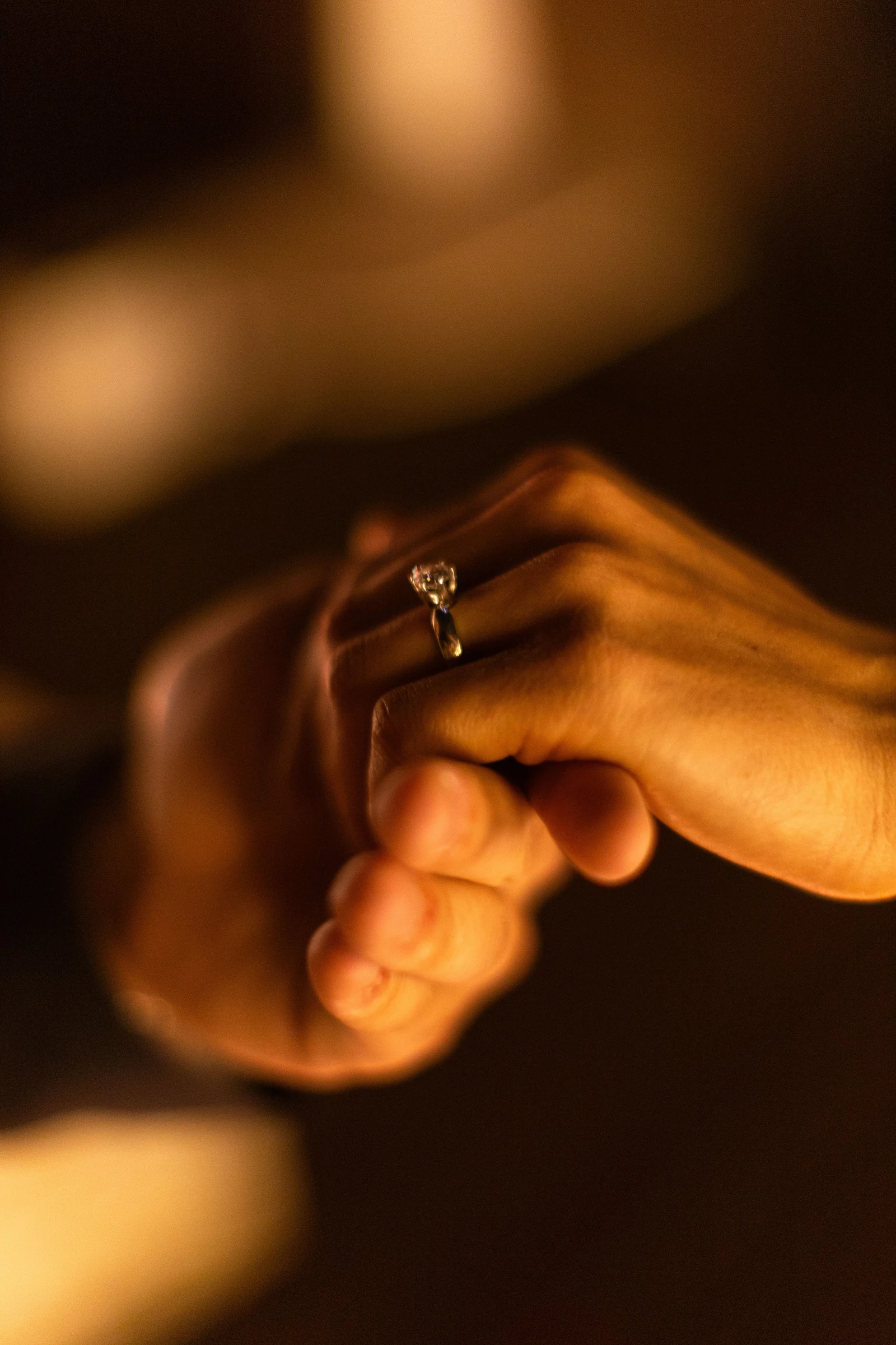 Main présentant une bague de fiançailles dans une lumière chaude