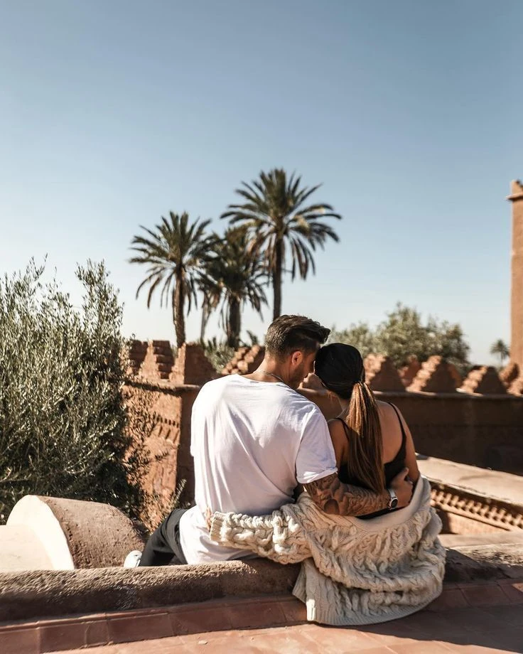 Couple assis sur un toit-terrasse, palmiers en arrière-plan