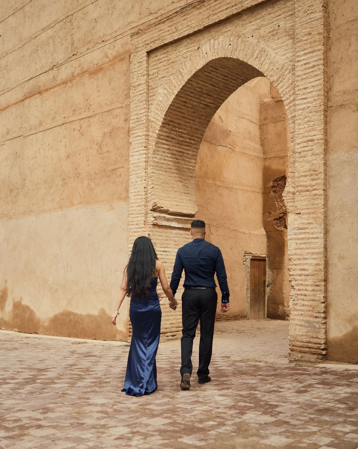 Couple marchant main dans la main vers une porte en arche